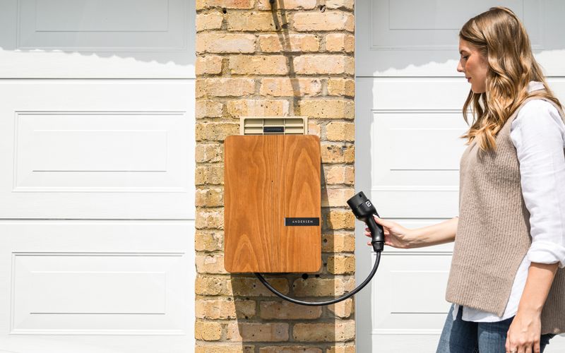 A home EV charger wall box mounted on a brick wall being used to charge a car