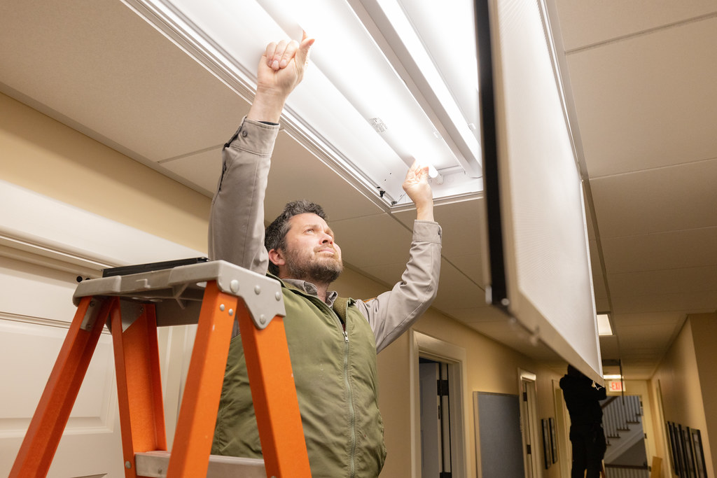 Electrician on a step ladder installing ceiling light fittings